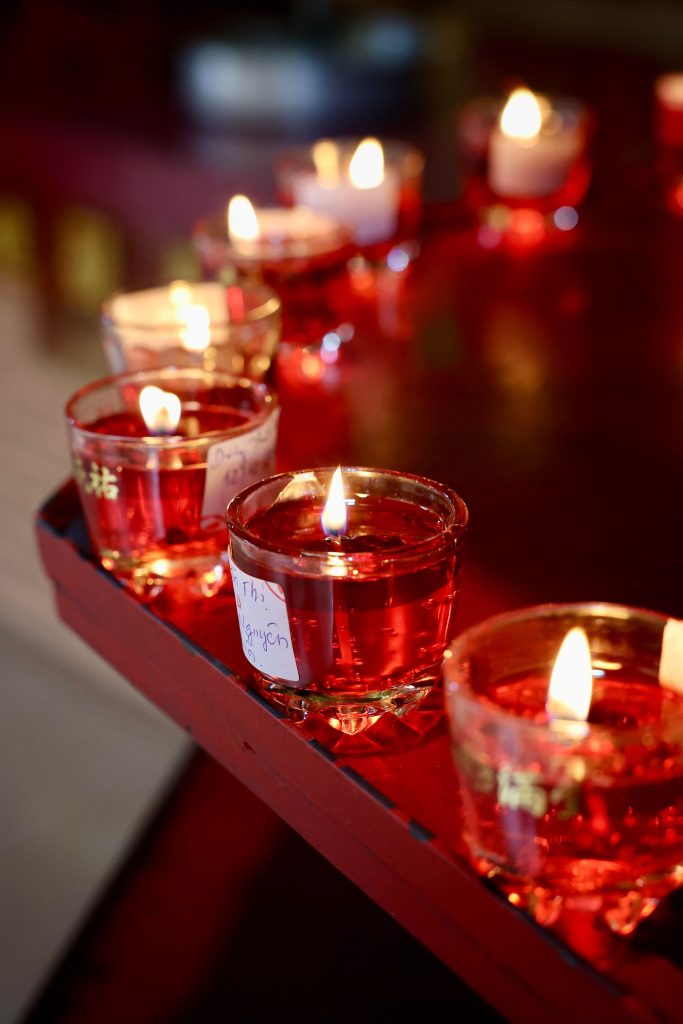 Close-up of red candles burning in glass holders on a red wooden surface, creating a warm ambiance.